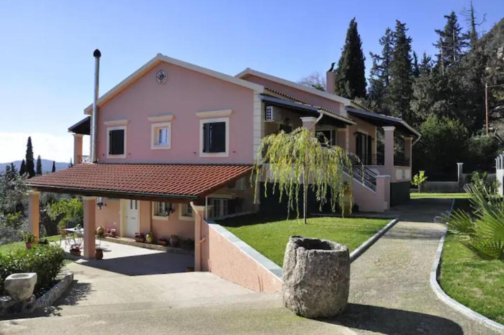 a pink house with a tree in front of it at Villa Leo Junior in Áno Korakiána
