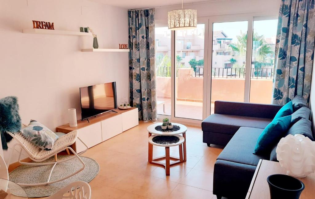 un salon avec un canapé bleu et une télévision dans l'établissement Spacious luxe apartment on Mar Menor Golf Resort with Padel, Fitness, Wellness facilities, à Torre-Pacheco