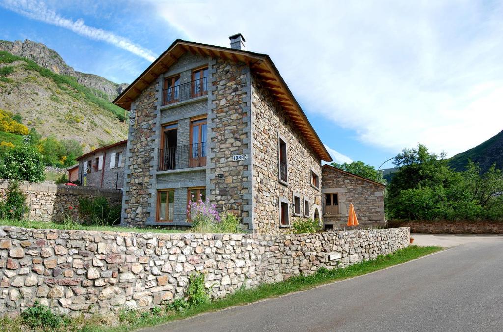 a stone building with a stone wall next to a road at Casa Rural Las Verdes l y II in Torre de Babia