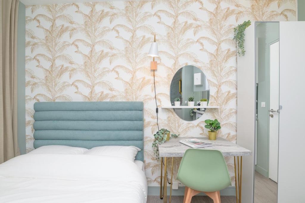 een slaapkamer met een bed, een tafel en een spiegel bij The Green Room - Duke Housing in Créteil