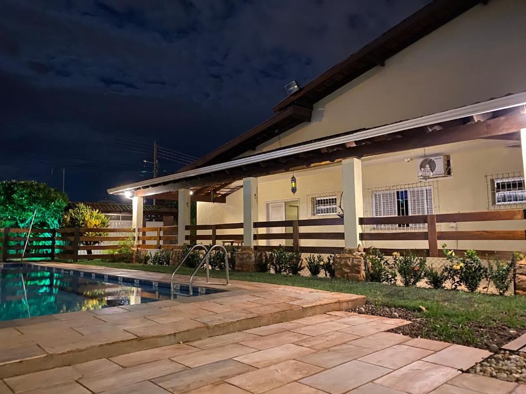 una casa con piscina por la noche en Pousada Vale do Rubi, en Londrina