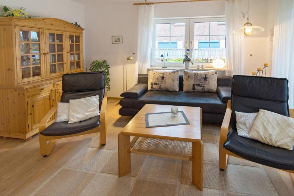ノルトダイヒにあるFerienwohnung Lütje Hörnのリビングルーム(ソファ、椅子、テーブル付)