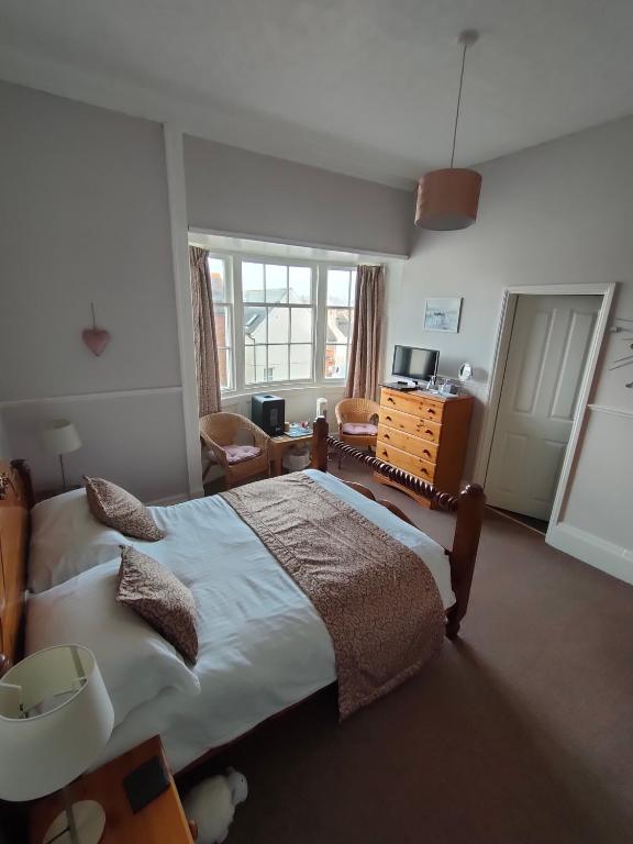 a bedroom with a large bed and a desk at Valentine Guest House in Weymouth