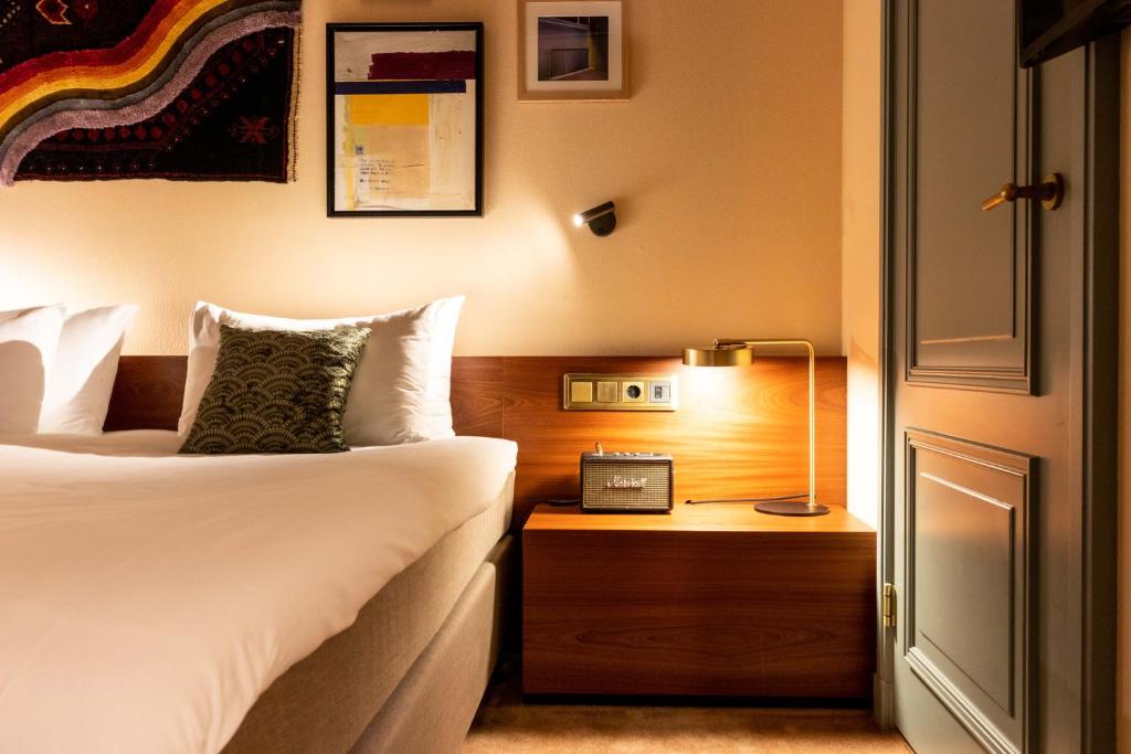 1 dormitorio con 1 cama y mesita de noche con lámpara en Hotel Mercier, en Ámsterdam