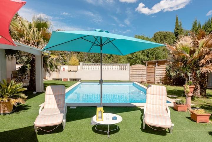 - une piscine avec 2 chaises et un parasol bleu dans l'établissement Villa CHRISALB 1, à Aix-en-Provence