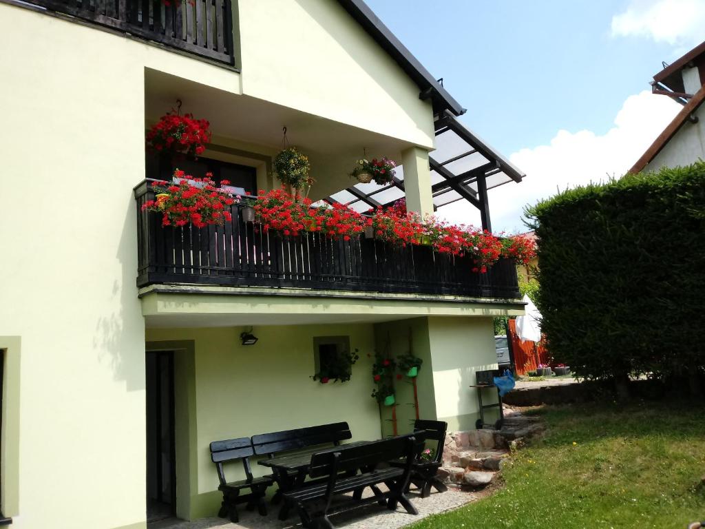 a building with a bench and flowers on a balcony at Pokoje gościnne Harnaś in Kudowa-Zdrój