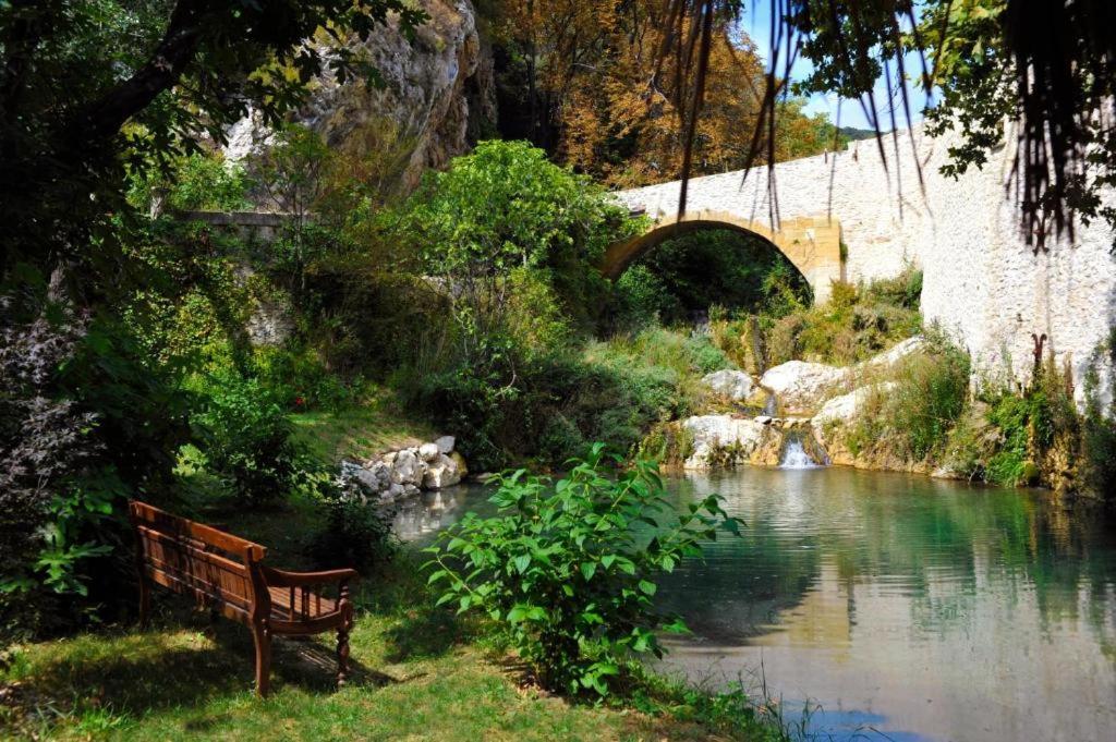 a bench sitting next to a river with a bridge at Hostellerie Le Paradou in Lourmarin