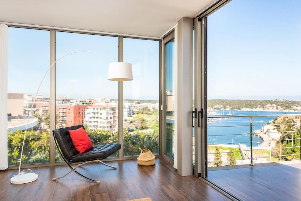 a living room with a chair and large windows at Blue Port in Mahón