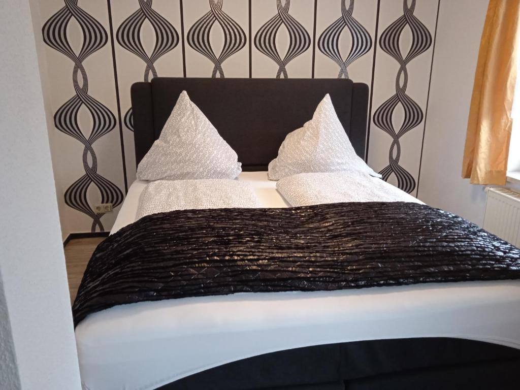 a bed with a black headboard and white sheets and pillows at Hotel & Restaurant Zum Adlersberg in Schleusingen