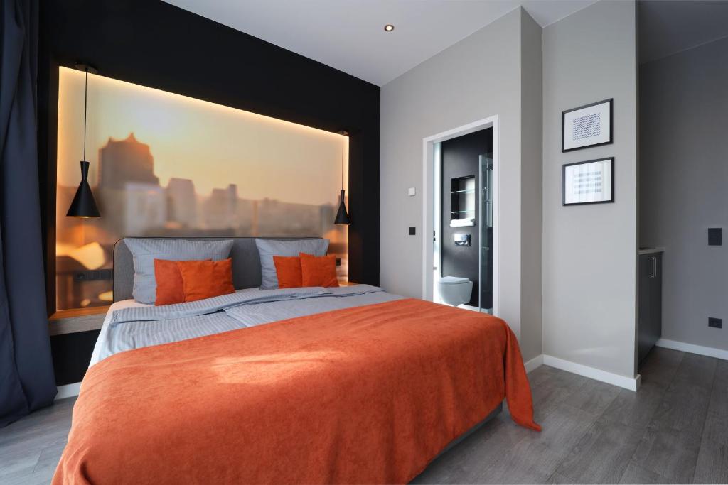 sypialnia z dużym łóżkiem i pomarańczowym kocem w obiekcie JustStay Ratingen w mieście Ratingen