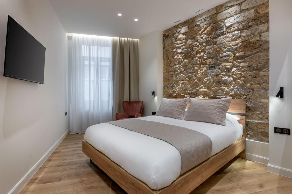 ein Schlafzimmer mit einem großen Bett und einer Steinmauer in der Unterkunft J&A Luxury Residence in Athen