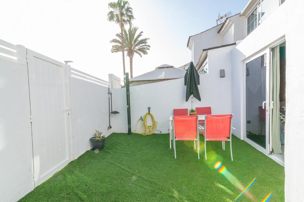 a patio with a table and chairs on a lawn at Deluxe Duplex Bungalow Private Parking in Maspalomas