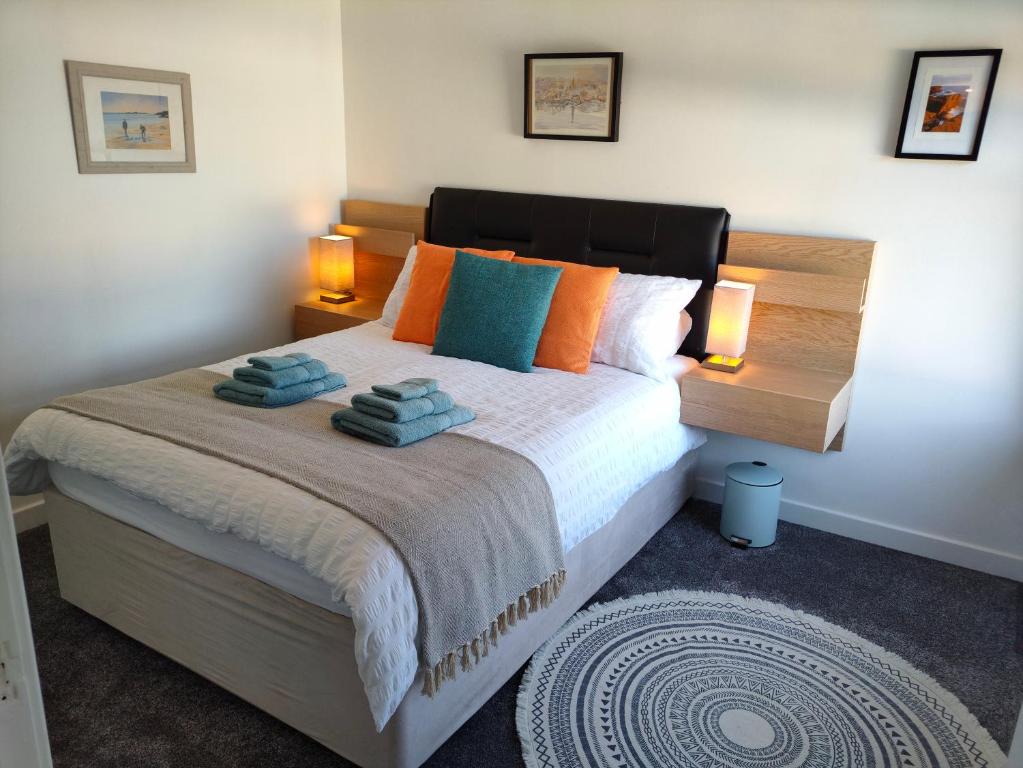 1 dormitorio con 1 cama con almohadas de color naranja y azul en Stromness Apartments, en Stromness