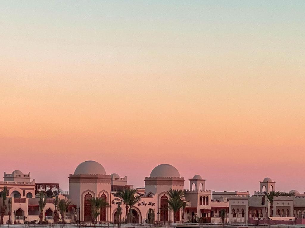 een uitzicht op een gebouw met een zonsondergang op de achtergrond bij Royal Suite on The Touristic Promenade in Hurghada