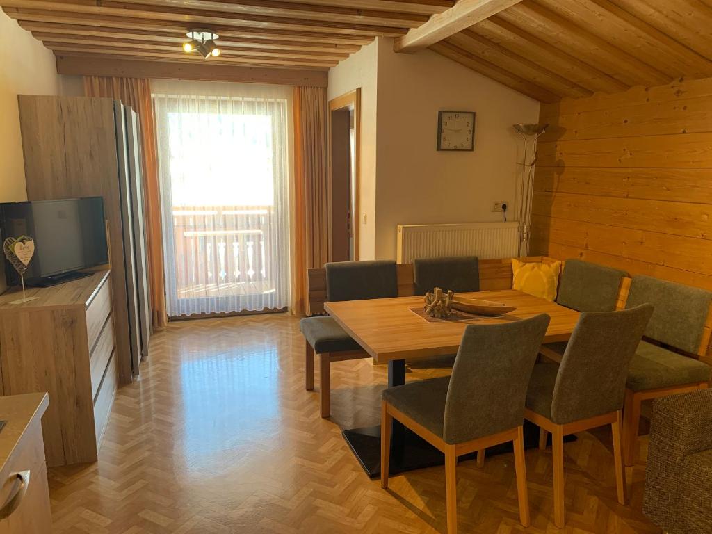 une salle à manger avec une table, des chaises et une télévision dans l'établissement Haus Hermi, à Nesselwängle