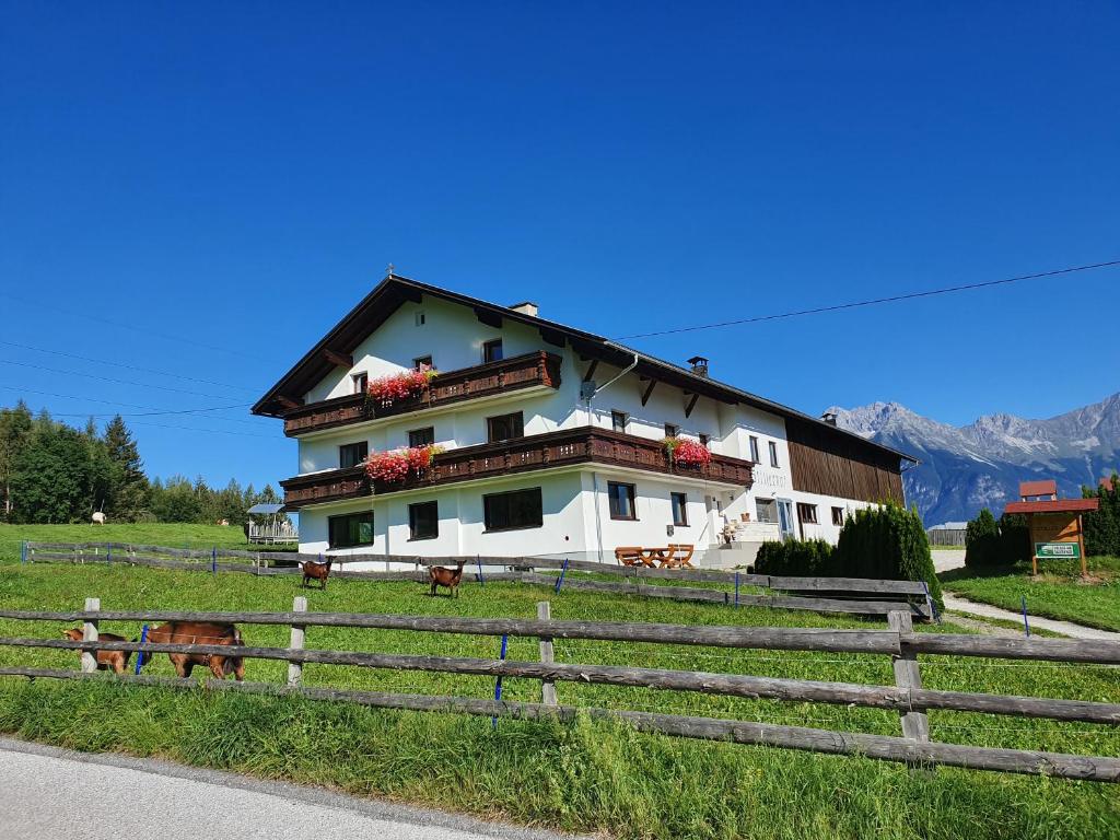 Ein weißes Haus mit einem Zaun auf einem Feld in der Unterkunft Ferienwohnung Stillerhof in Innsbruck