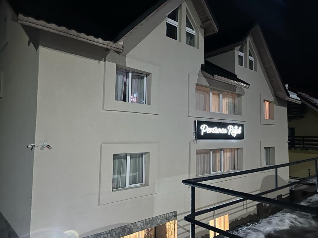a white building with a sign on the side of it at Pensiunea Royal in Ranca