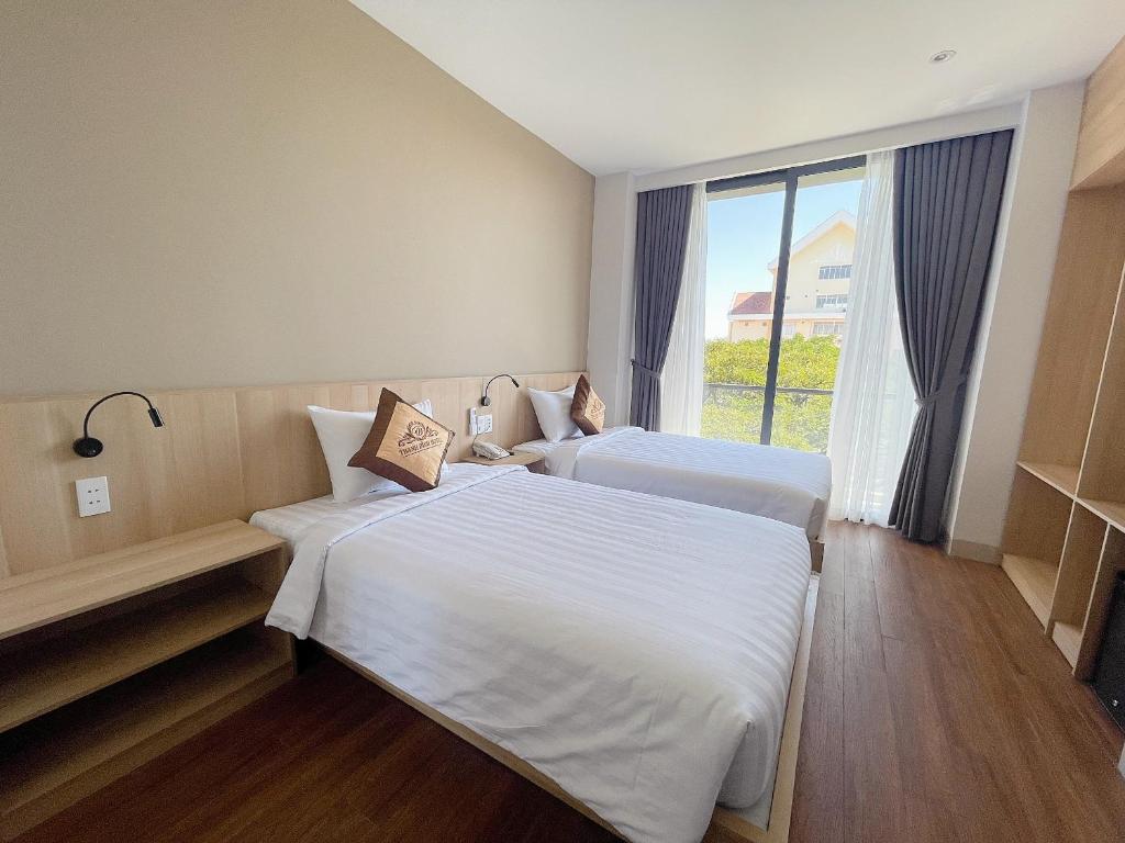 two beds in a hotel room with a window at Thanh Bình Hotel - 47 Y Bih - BMT in Buon Ma Thuot