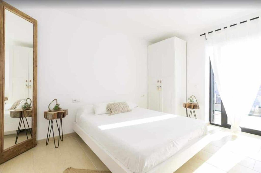 1 dormitorio blanco con 1 cama grande y espejo en Maravilloso apto de diseño a 1 minuto de la playa, en Cala Santandria