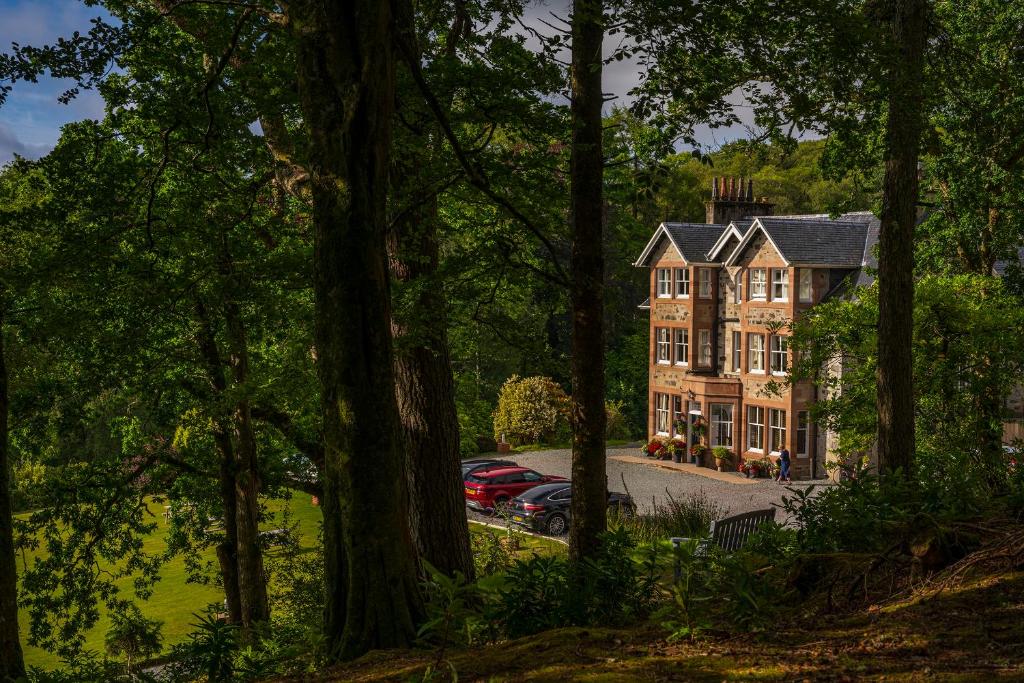 uma casa grande com carros estacionados em frente em Duisdale House Hotel em Isleornsay