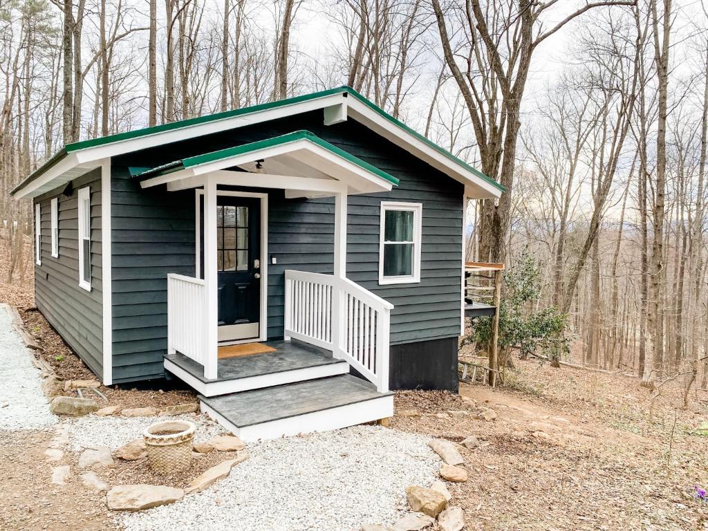 une petite maison bleue avec une terrasse couverte dans les bois dans l'établissement Mountain Retreat Nesteled in the Virginia Foothills, à Charlottesville