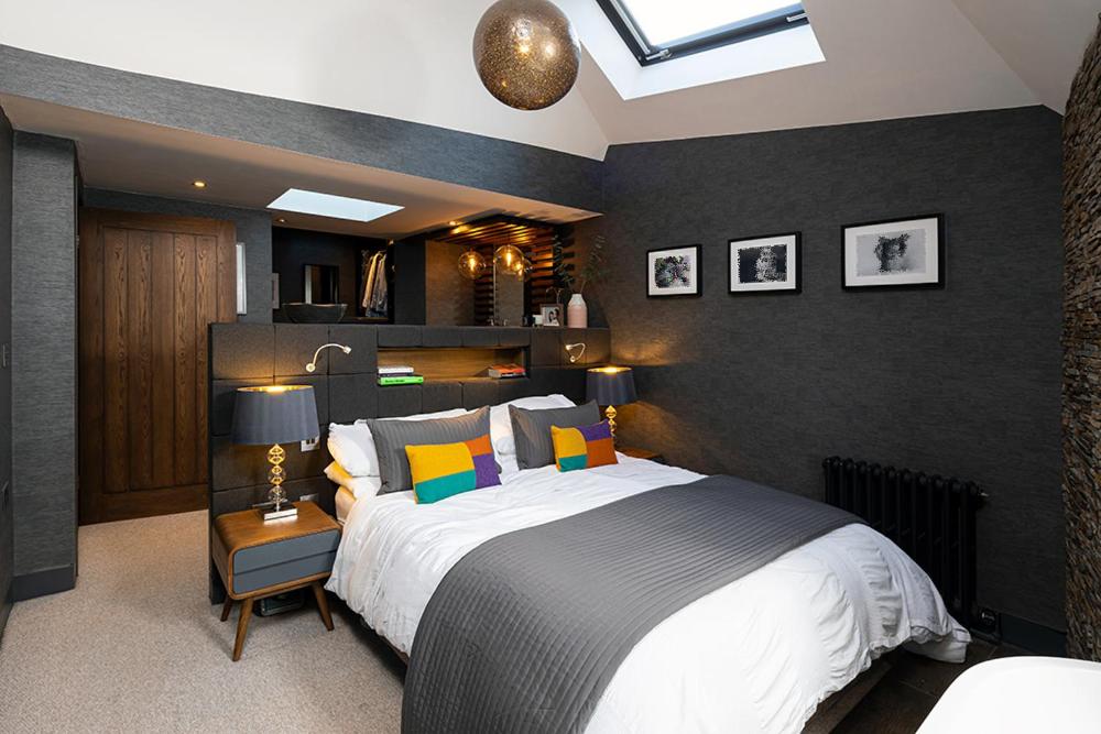 sypialnia z dużym łóżkiem z czarną ścianą w obiekcie Roselea Cottage w mieście Luss