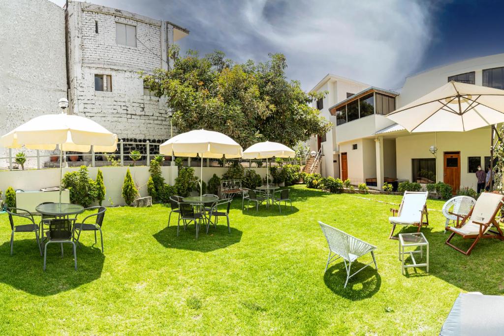 einen Garten mit Tischen, Stühlen und Sonnenschirmen in der Unterkunft Hotel El Turista in Arequipa