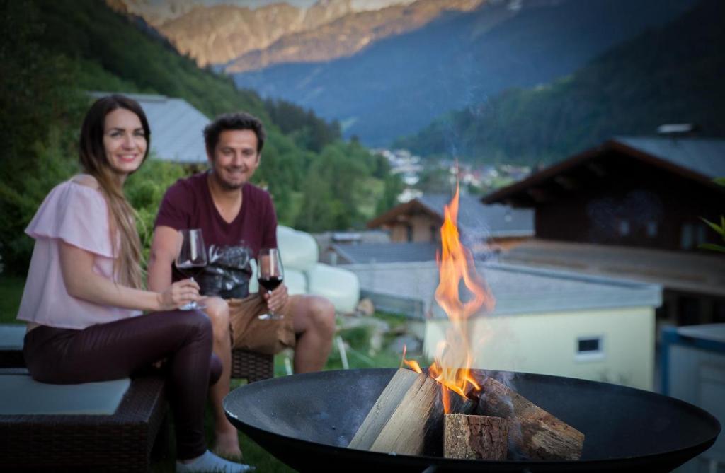 mężczyzna i kobieta siedzący obok ogniska w obiekcie Alpenzauber Apartment Montafon w mieście St. Gallenkirch