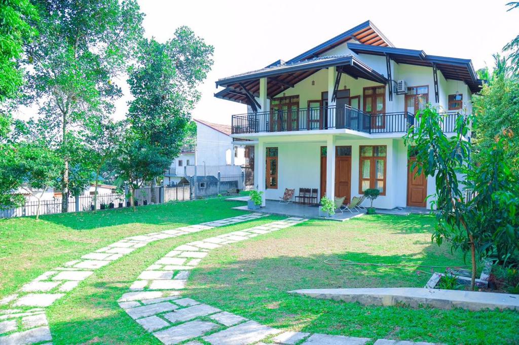 une maison avec une passerelle en pierre devant elle dans l'établissement SaDev Lake Villa Bandaragama, à Bandaragama