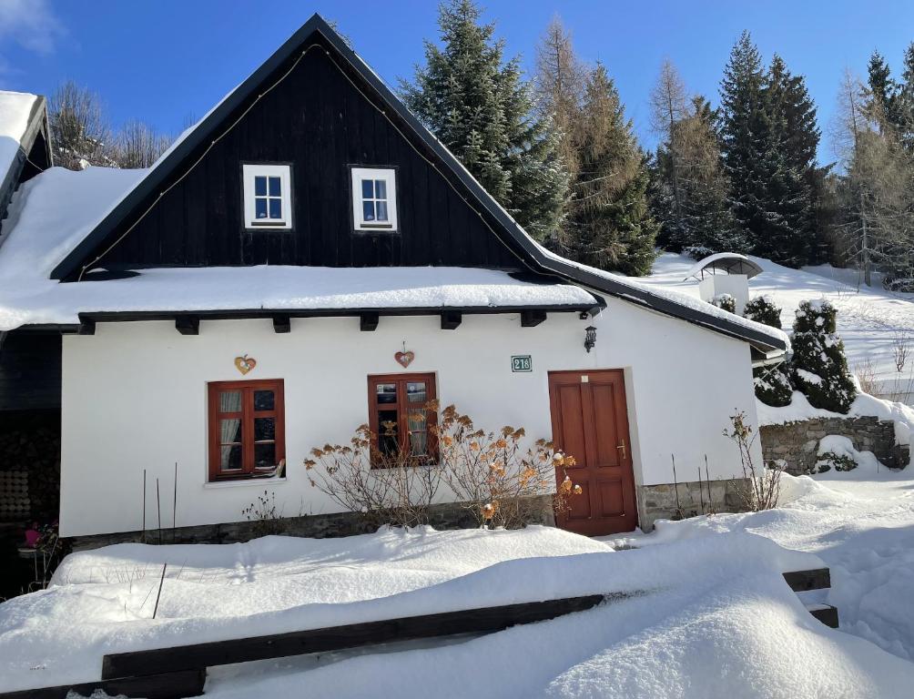 una casa bianca con un tetto nero nella neve di Rozpravkovy Domcek Zvoncek a Donovaly