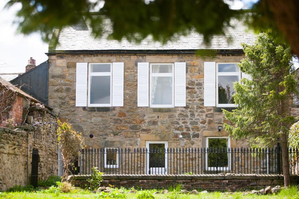 an old brick house with white windows and a fence at White Swan Cottage in Alnwick