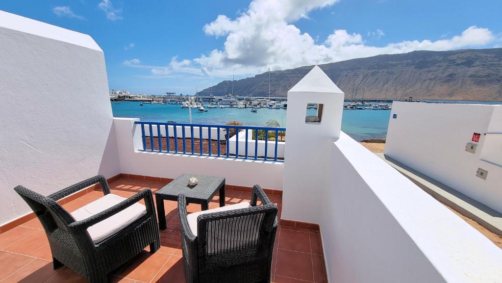 a balcony with two chairs and a table and a view of the water at La Graciosa Mykonos Beach, Junior Suite in Caleta de Sebo