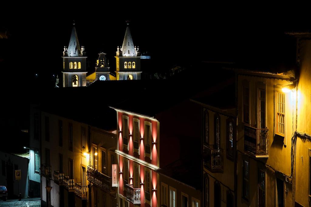 a city at night with a clock tower in the background at Memória Boutique Hostel in Angra do Heroísmo