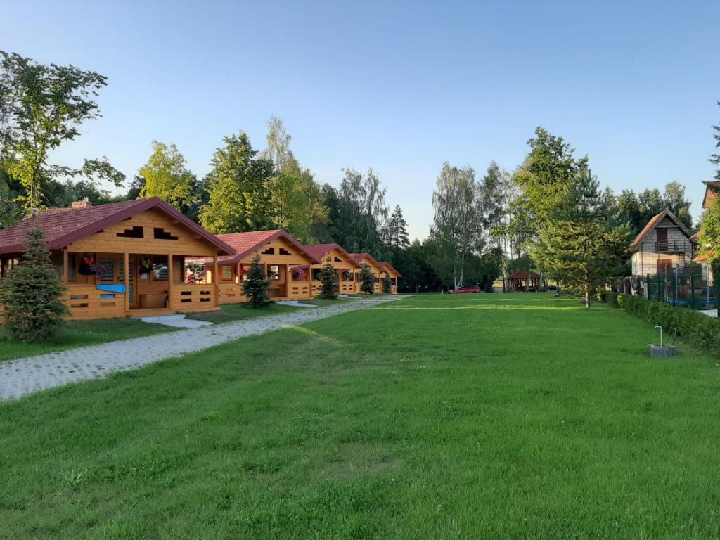 une grande cour en face d'une cabane en rondins dans l'établissement Domki nad jeziorem Kolonia Rybacka, à Kolonia Rybacka