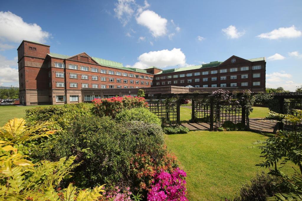 a large brick building with flowers in a yard at The Golden Jubilee Hotel in Clydebank