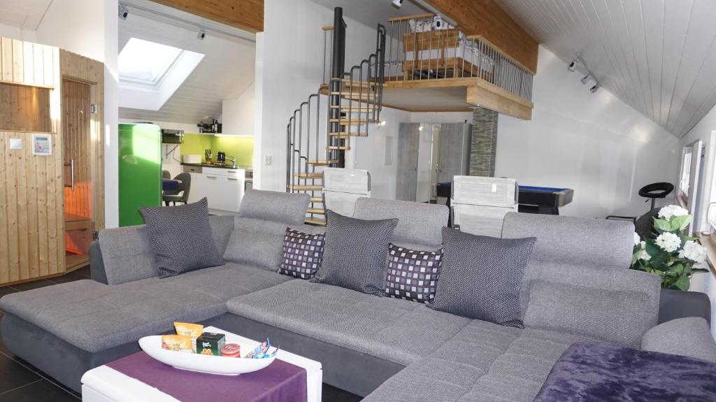uma sala de estar com um sofá cinzento e uma escada em Loft in der Natur mit Gartenzugang und Sauna em Herisau