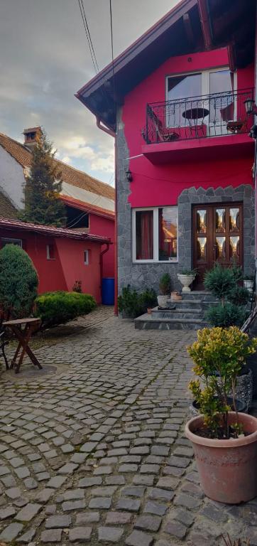 a red house with a brick patio in front of it at Casa Terzea in Râşnov