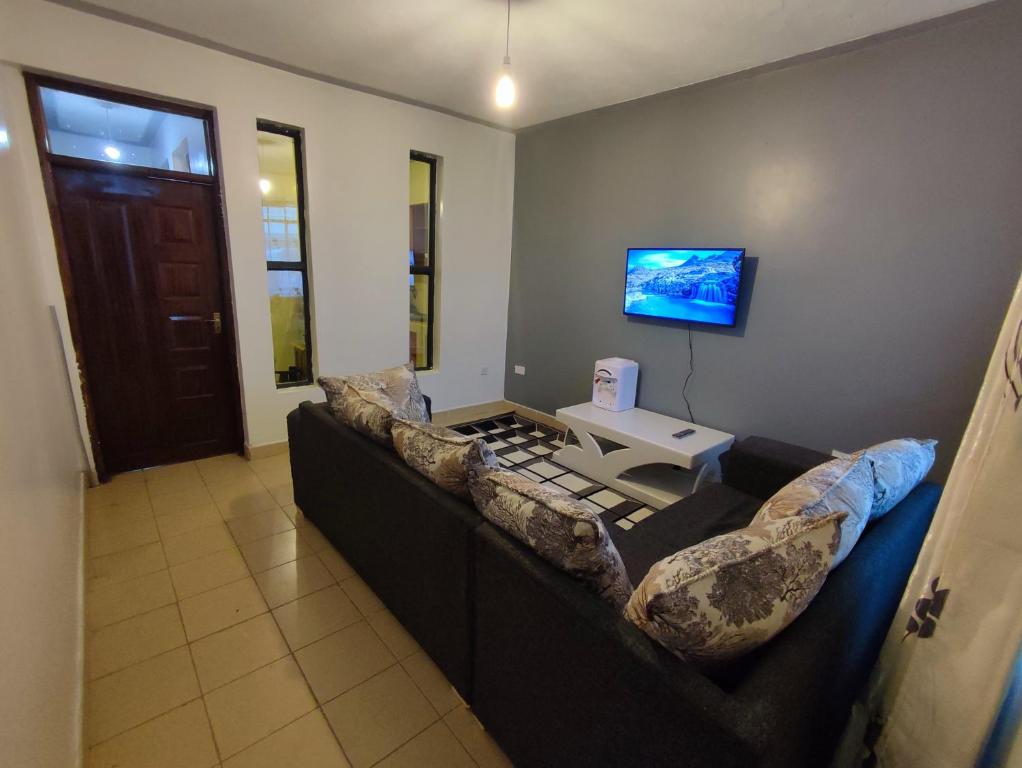 ASHÉ في نيفاشا: غرفة معيشة مع أريكة سوداء وتلفزيون