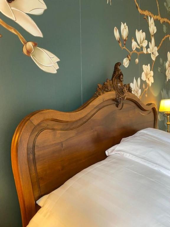 a bed with a wooden head board with flowers on the wall at Maison de l'Aumance in Meaulne