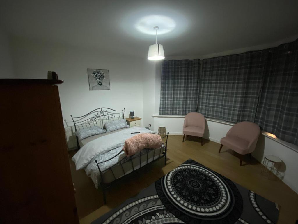 1 dormitorio con 1 cama y 2 sillas rosas en Lovely 2 Bedroom Apartment with free parking en Mánchester