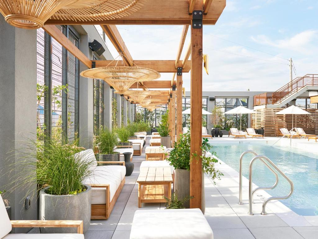 an outdoor patio with a pool and tables and benches at The Rockaway Hotel in Queens
