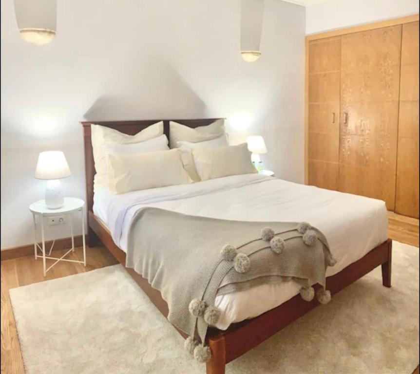 1 dormitorio con 1 cama grande con almohadas blancas en TOP BEACH HOUSE, en Costa da Caparica