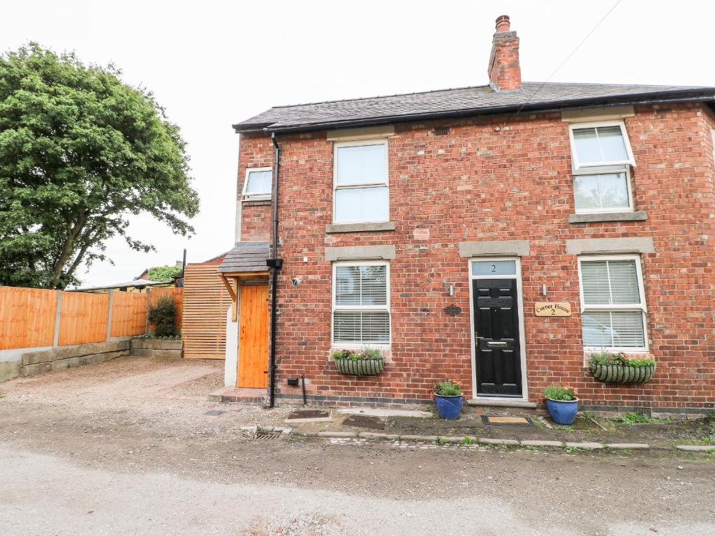 an old red brick house with a black door at Corner House Cottage in Ilkeston