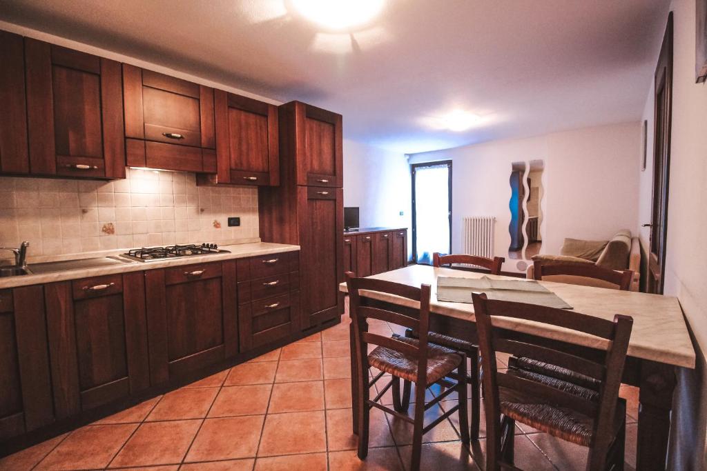 una cocina con armarios de madera y una mesa con sillas. en Residence Aquila - Bilo Testa di Comagna, en Brusson