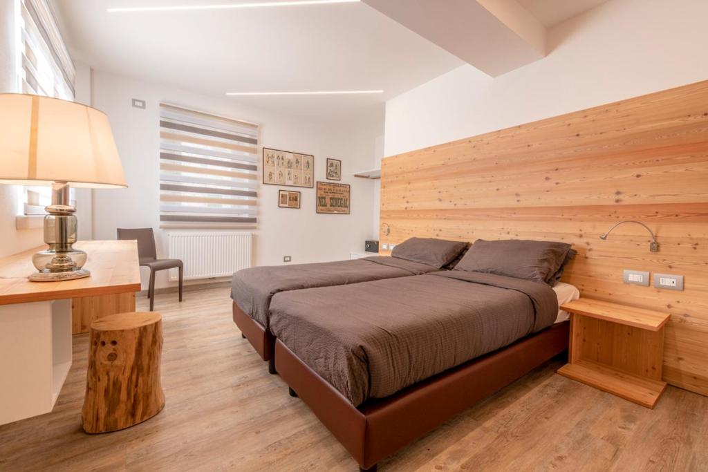 - une chambre avec un grand lit et un mur en bois dans l'établissement Sweet Dolomites Sauna & Jacuzzi, à Agordo