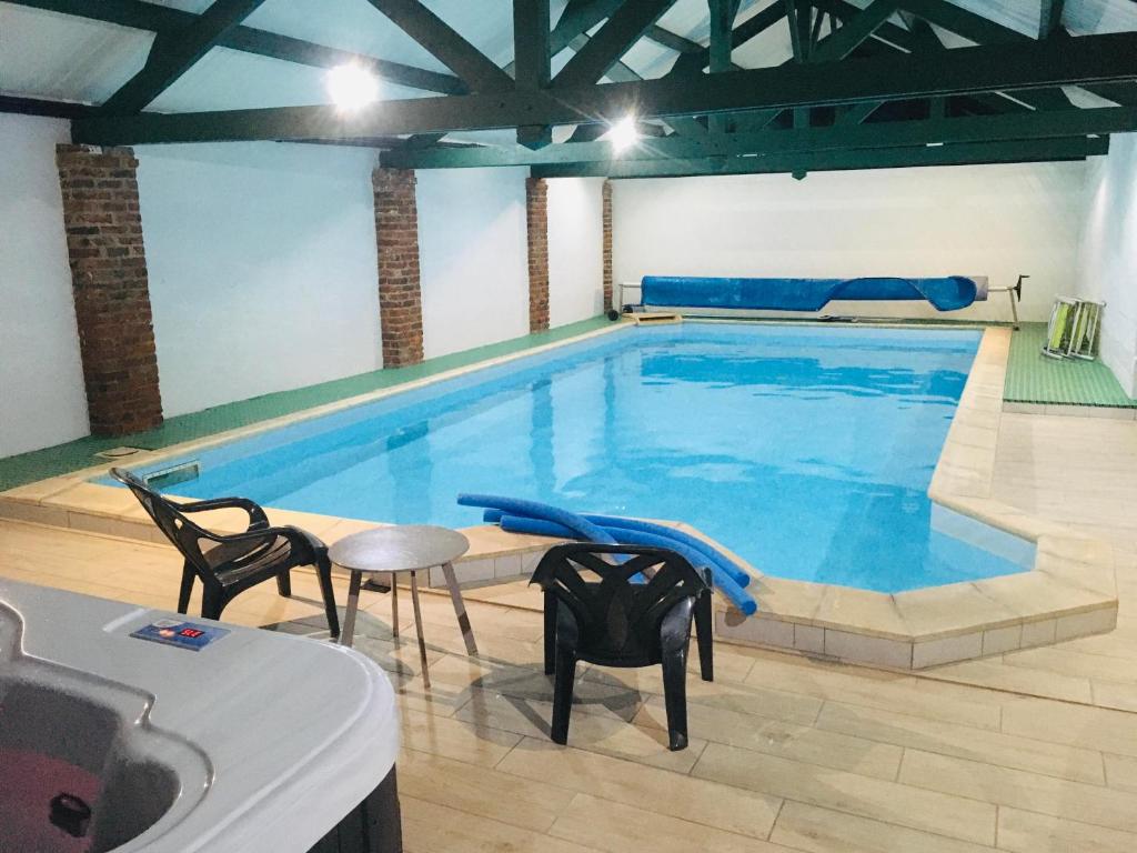 a large swimming pool with chairs and a table in front of it at Les Chambres de Saint Hilaire in Saint-Hilaire-Cottes