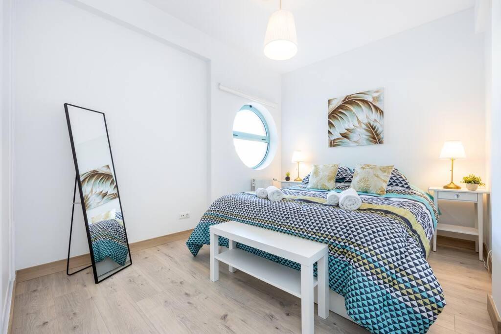 a white bedroom with a bed and a mirror at Casa das Cores in Albufeira