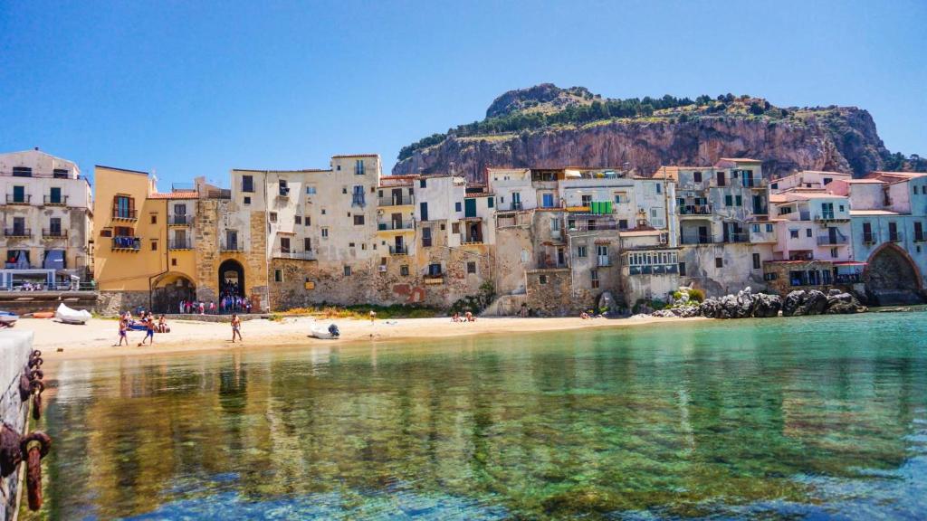 a group of buildings on a beach next to the water at Kasamare apartments in Cefalù