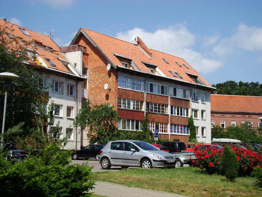 een groep gebouwen met auto's geparkeerd op een parkeerplaats bij Apartamentai Ramybė in Nida