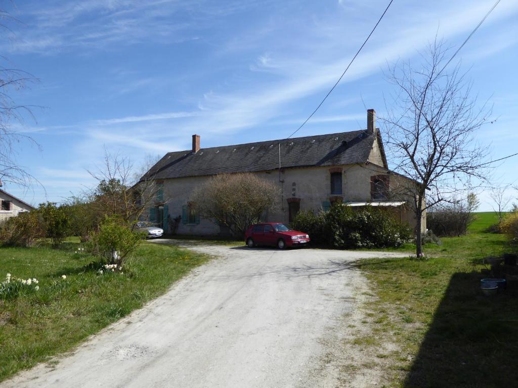 a house with a red car parked next to a dirt road at joli gite au calme proche d'Issoudun (17 km) in Giroux